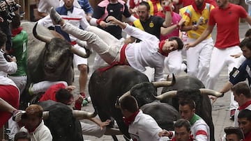Astados de la ganadería de Miura, de Lora del Río (Sevilla), voltean a un mozo en el tramo final que precede al callejón de entrada a la Plaza de Toros durante el octavo y último encierro de los Sanfermines 2017.