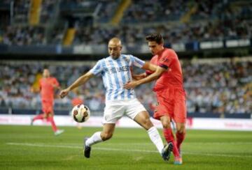 El delantero marroquí del Málaga CF Nordin Amrabat lucha el balón con el defensa del FC Barcelona Marc Bartra, durante el encuentro de la quinta jornada de Liga en Primera División que se disputa esta noche en el estadio de La Rosaleda, en Málaga.
