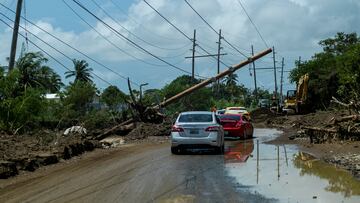 Cars drive under a downed power pole in the aftermath of Hurricane Fiona in Santa Isabel, Puerto Rico.