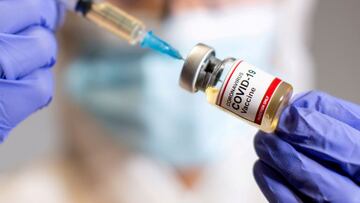 FILE PHOTO: A woman holds a small bottle labeled with a &quot;Coronavirus COVID-19 Vaccine&quot; sticker and a medical syringe in this illustration taken  October 30, 2020. REUTERS/Dado Ruvic/File Photo/File Photo