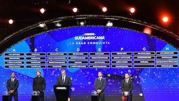 Conmebol's director of competitions and operations Frederico Nantes (C) and ex-footballers Mauro Silva (L) of Brazil, Diego Lugano (2-L) of Uruguay, Ricardo Tavarelli (2-R) of Paraguay and Maximiliano Rodriguez of Argentina, stand under the screen displaying the fixture of the group phase of the Sudamericana Cup football tournament, during the draw at Conmebol's headquarters in Luque, Paraguay, on March 27, 2023. (Photo by NORBERTO DUARTE / AFP)