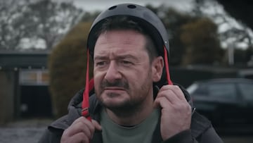 El adulto protagonista del anuncio de John Lewis para la Navidad 2022 intentando abrocharse el casco de protecci&oacute;n para el skate. 
