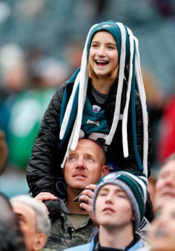 La hija está disfrutando del partido de los Eagles. Es joven y no tiene preocupaciones. El padre está más preocupado de no perder el ojo de un latigazo.