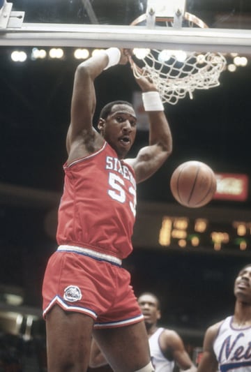 No fue un pívot históricamente dominante, aunque podría haberlo sido con más ética de trabajo por sus incuestionables facultades. Pero sí fue uno de los personajes más queridos y carismáticos de su época: Darryl Dawkins, Chocolate Thunder, era un 2,11 de 115 kilos que jugó en la NBA entre 1975 y 1989 y después pasó por Turín y Milán. Stevie Wonder le dio su apodo y él patentó unos mates tremendos a los que ponía nombre... y con los que rompió un tablero en 1979 y otras tres semanas después. El comisionado Larry O'Brien le dijo que se había un tercero se llevaría una suspensión y una multa de 5.000 dólares, y al final de esta temporada, la NBA cambió los aros y su unión con el tablero por un sistema más flexible que aceptaba mejor la tremenda presión que imprimía la llegada de un nuevo tipo de matadores. El siguiente que cobró fama por reventar aros fue, ya mucho después, Shaquille O'Neal. Dawkins solía decir que era un alienígena que venía del planeta Lovetron, donde practicaba junto a su pareja, Juicy Lucy, lo que llamaba interplanetary funkmanship. Al primer mate con el que reventó un aro lo llamó 'The Chocolate-Thunder-Flying, Robinzine-Crying, Teeth-Shaking, Glass-Breaking, Rump-Roasting, Bun-Toasting, Wham-Bam, Glass-Breaker-I-Am-Jam'.