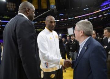 Kobe Bryant saluda a Thomas Bach (presidente del Comité Olímpico Internacional) ante Magic Johnson.