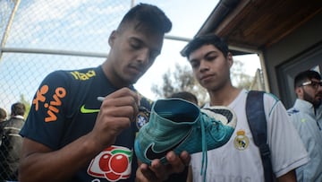 Gabriel Menino firma un aut&oacute;grafo en una bota a un aficionado con una camiseta del Real Madrid durante una concentraci&oacute;n con Brasil sub-20.