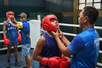 El entrenador Larry Semillano (derecha) poni¨¦ndole un casco a un joven durante el entrenamiento.