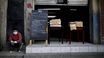 A man sits as he offers food for sale during a government-ordered lockdown to curb the spread of the new coronavirus at a slum in Buenos Aires, Argentina, Sunday, April 26, 2020. (AP Photo/Natacha Pisarenko)