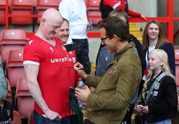 El actor y copropietario del Wrexham, Ryan Reynolds, firma autógrafos para los aficionados antes del partido.
