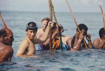 El futuro rey de Reino Unido pescando con una lanza de madera junto a un grupo de isleños en 1975.   