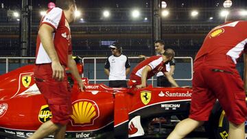 Alonso speaks to his former teammates from Ferrari as they push a car past at the pit ahead of the Singapore F1 Grand Prix night race in Singapore September 17, 2015. 