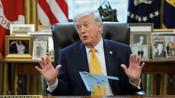 U.S. President Donald Trump gestures in front of a model aircraft commemorating "Operation Midnight Hammer", according to its inscription, during an event to sign an executive order creating an anti‑fraud task force headed by U.S. Vice President JD Vance in the Oval Office at the White House in Washington, D.C., U.S., March 16, 2026. REUTERS/Jonathan Ernst