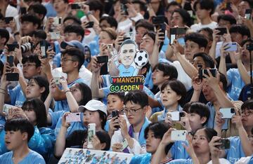 Aficionados coreanos del Manchester City con sus m¨®viles grabando el entrenamiento del conjunto mancuniano. Se aprecia una figura de cart¨®n con la cara de Phil Foden.