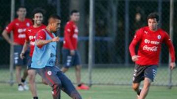 El jugador de la selección nacional de Chile Arturo Vidal toca un balón ante Eugenio Mena durante el entrenamiento vespertino en el complejo deportivo Toca da Raposa II hoy, domingo 15 de junio de 2014, en Belo Horizonte (Brasil). El combinado nacional prepara su segundo partido de la Copa del Mundo contra España el próximo día 18 de junio en Río de Janeiro.