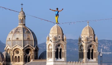 Una funambulista, con la catedral de Santa María la Mayor de la ciudad de Marsella a su espalda, durante un evento que forma parte de la nominación de la ciudad como capital del deporte.