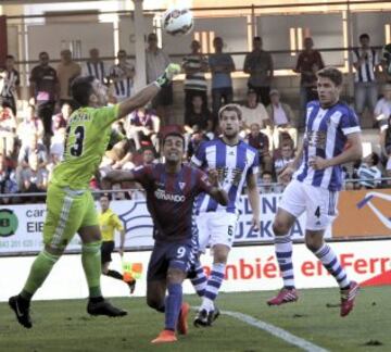 El portero de la Real Sociedad Eñaut Zubikarai (i) despeja el blaón ante el delantero del Eibar Ángel Rodríguez (2i) durante el partido de la primera jornada de Liga de Primera División disputado en el estadio de Ipurua. 