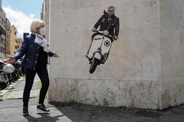 Una mujer pasa sorprendida junto a un mural, en el distrito romano de Testaccio, en el que aparece la imagen de
Mourinho montado en una Vespa con una bufanda con los colores de su nuevo equipo: la AS Roma. El técnico portugués
ha firmado con el club italiano por tres años y sustituirá a Paulo Fonseca a final de la presente temporada.