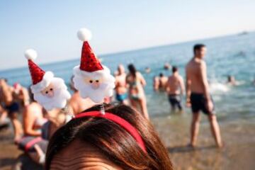 Decenas de ciudadanos participaron este mediodía en el tradicional primer baño del año en la playa de Sant Sebastià del barcelonés barrio de la Barceloneta.