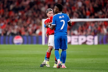 El jugador argentino del Benfica se tapa la boca con la camiseta y algo le dice a Vinicius.