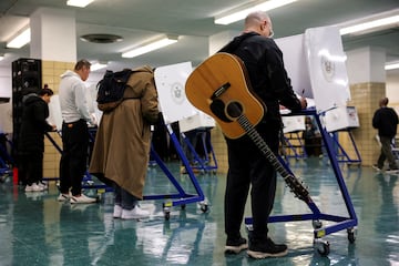 Un hombre con una guitarra votando en la escuela primaria P.S. 140 Nathan Straus en Manhattan, Nueva York.