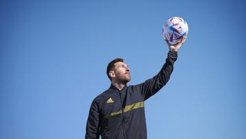 Lionel Messi sostiene un balón con su mano izquierda.