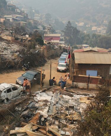 La gente se abraza junto a los restos quemados de una casa tras la propagación de incendios forestales, en Viña del Mar, Chile. 