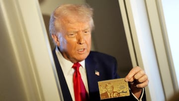 U.S. President Donald Trump holds "The Trump Card" as he speaks with journalists onboard Air Force One en route to Miami, Florida, U.S., April 3, 2025. REUTERS/Kent Nishimura TPX IMAGES OF THE DAY