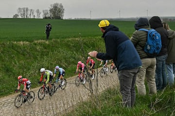 Un grupo de ciclistas avanza entre los espectadores en una zona pavimentada durante la 122.? edici¨®n de la cl¨¢sica carrera ciclista de un d¨ªa Par¨ªs-Roubaix.