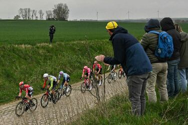 Un grupo de ciclistas avanza entre los espectadores en una zona pavimentada durante la 122.ª edición de la clásica carrera ciclista de un día París-Roubaix.