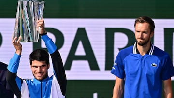Spain's Carlos Alcaraz (L) lifts the championship trophy after defeating Russia's Daniil Medvedev (R) in the ATP-WTA Indian Wells Masters men's final tennis match at the Indian Wells Tennis Garden in Indian Wells, California, on March 17, 2024. (Photo by Frederic J. BROWN / AFP)