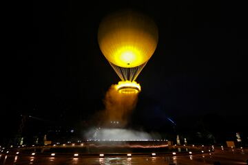 Teddy Riner y Marie-Jose Perec encienden la llama olímpica y observan como se eleva el pebetero en un globo.