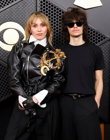 Miley Cyrus y Maxx Morando posan en la alfombra roja.