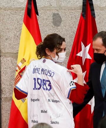 Isabel Díaz Ayuso recibe como obsequio una camiseta firmada por los miembros de la "Quinta del Buitre".
