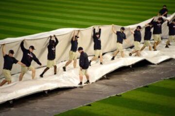 Miembros del staff de los Cleveland Indians quitan la lona que tapaba el césped para resguardarlo de la lluvia, antes del partido ante los Chicago Cubs.