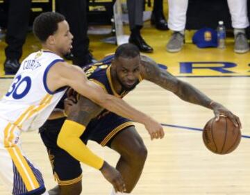 LeBron James, el jugador de los Cavaliers intenta desmarcarse de Stephen Curry, de los Warriors,  al termino del tercer partido de la serie final de la NBA