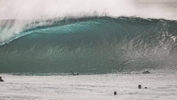 La ola de El Quemao con un surfista levantanzo los brazos y el labio del tubo a punto de romper. Varios surfistas y bodyboarders se lo miran.