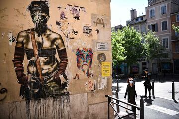 A man wearing a face mask walks past a graffiti in Marseille, southern France on April 25, 2020, as the country is under lockdown to stop the spread of the Covid-19 pandemic caused by the novel coronavirus.