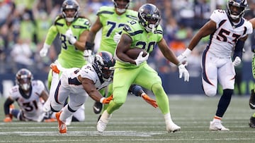 Rashaad Penny of the Seattle Seahawks carries the ball past Jonas Griffith of the Denver Broncos during the second quarter at Lumen Field on September 12, 2022 in Seattle, Washington.