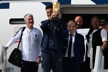 's goalkeeper Hugo Lloris (2nd L) holds the trophy as he disembarks from the plane next to 's coach Didier Deschamps (L), French Football Federation president Noel Le Graet (2nd R) and French Sports Minister Laura Flessel (R) upon their arrival at the Roissy-Charles de Gaulle airport on the outskirts of Paris, on July 16, 2018 after winning the Russia 2018 World Cup final football match. / AFP PHOTO / Lionel BONAVENTURE