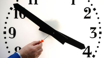 This file photo taken on March 26, 2014 shows an employee of the Bodet Company setting a clock at the plant of Trementines, western France. - 