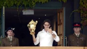 Roger Federer saluda a los aficionados con el trofeo de Wimbledon en la mano.