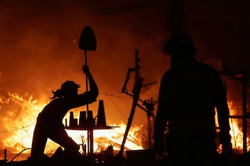 Un ninot de un voluntario que ayuda a limpiar el barro de las inundaciones se alza durante el ltimo da de las Fallas en Valencia.