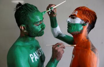 Dos aficionados al críquet se ayudan mutuamente a pintarse los cuerpos con los colores de las banderas nacionales de India y Pakistán, antes del partido que enfrentó a sus selecciones en la Copa Mundial ICC que se disputa en Ahmedabad (India). Entrañables amigos en la calle y acérrimos enemigos en la grada.