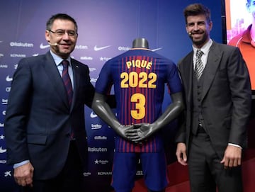 Barcelona's Spanish defender Gerard Pique poses beside his jersey and Barcelona FC president Josep Maria Bartomeu.