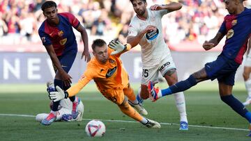 Valladolid's goalkeeper Karl Hein, bottom, fails to save a goal by Barcelona's Raphinha, right, during the Spanish La Liga soccer match between FC Barcelona and Valladolid at the Olympic stadium in Barcelona, Spain, Saturday, Aug. 31, 2024. (AP Photo/Joan Monfort)
