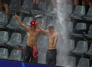 Dos aficionados daneses bailan bajo la cascada de agua que caía en su zona.