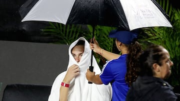 La tenista Aryna Sabalenka se cubre de la lluvia con una toalla durante su partido ante Elena Rybakina en las WTA Finals de Cancún.