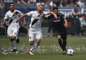 Perry Kitchen y Carlos Vela luchan por la esférica en el StubHub Center de California.