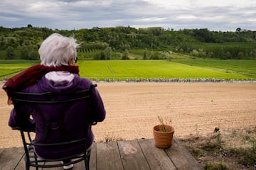 Una mujer de avanzada edad observa en soledad, desde la distancia, el paso de los corredores entre extensos campos de labranza durante la tercera etapa del Giro de Italia. El recorrido, de 166 kilómetros prácticamente llanos entre las localidades de Novara y Fossano, discurrió por los bellos paisajes del Piamonte italiano.