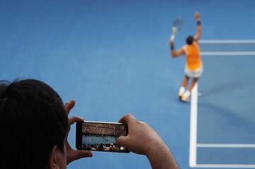 un espectador realiza una fotografía desde su teléfono móvil a Rafa Nadal durante un saque del tenista español.